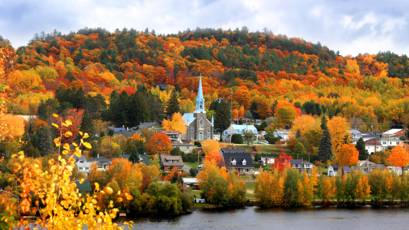 Village pittoresque avec une église entourée d'arbres aux couleurs automnales