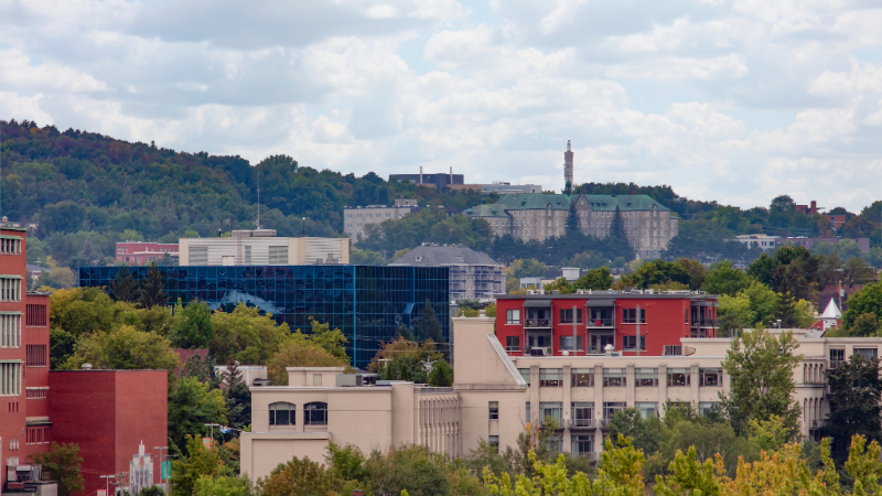 Vue urbaine avec des bâtiments modernes et une colline boisée en arrière-plan